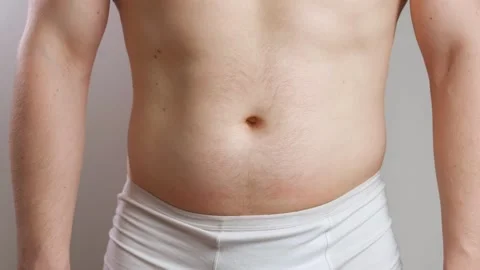 A man in white underpants pulls in a big belly and strains his abs in close-up Stock Footage 241415316