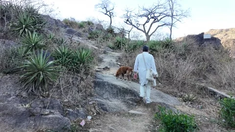 A man in white walks up a steep mountain path Stock Footage 330332407