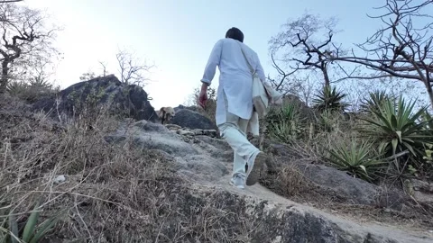 A man in white walks up a steep mountain path Vídeo Stock 330332410