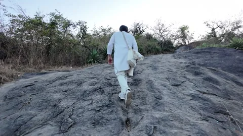 A man in white walks up a steep mountain path Stock Footage 330332415