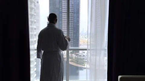 Man who drinks coffee and looks at the city through the windows of a skyscraper. Stock Footage 265991990