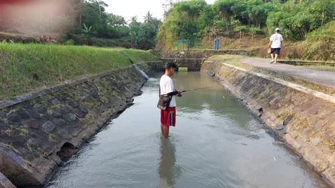 A man who is fishing using a casting technique in a river Stock Photos