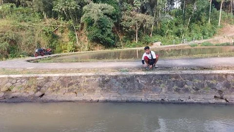 A man who is fishing using a casting technique in a river Stock Photos