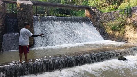 A man who is fishing using a casting technique in a river Stock Photos