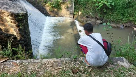 A man who is fishing using a casting technique in a river Stock Photos