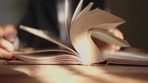 A man who opens a book and reads a book on the table Stock Footage 148101573
