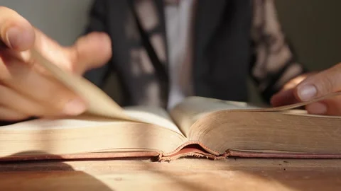 A man who opens a book and reads a book on the table Stock Footage 148101736