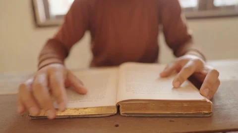 A man who opens a book and reads a book on the table Stock Footage 148101946