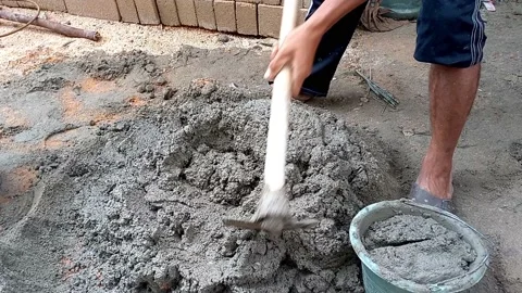 A Man Who Is Putting Cement Mixture Into A Black Bucket Stock-Footage 236355476