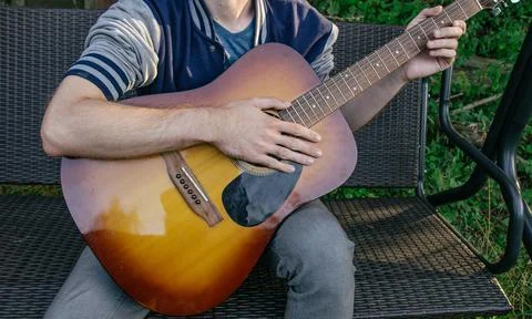 A man, whose face is not visible, plays the guitar on a musical instrument, s Foto stock