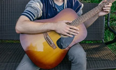 A man, whose face is not visible, plays the guitar on a musical instrument, s Foto stock