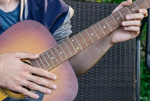 A man, whose face is not visible, plays the guitar on a musical instrument, s Foto stock
