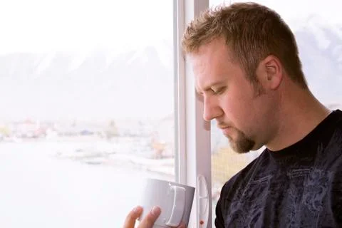Man by the window with a cup of coffee Stock Photos
