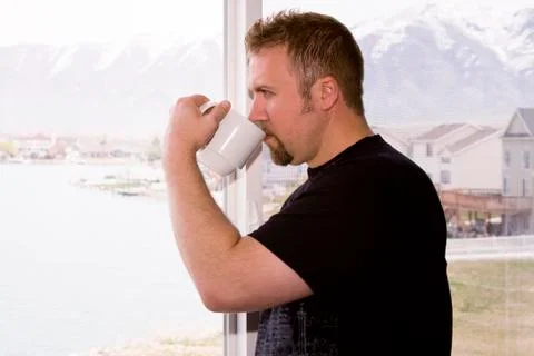 Man by the window with a cup of coffee Stock Photos