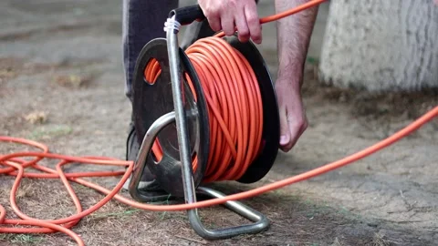 A man winds the cable with electric cable reel Stock Footage 200129500