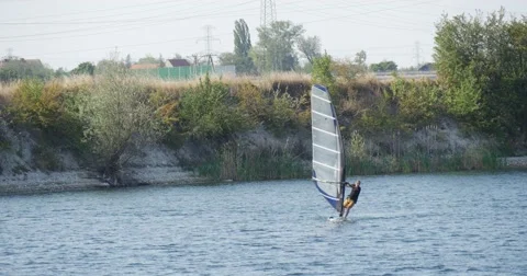 Man on The Windsurf Board With Sail is Floating Fast by Watery Surface along Stock Footage 53609033