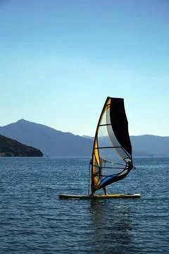 Man on a windsurf in the sea. Man learning to windsurf in the bay. Windsurfing. Stock Photos