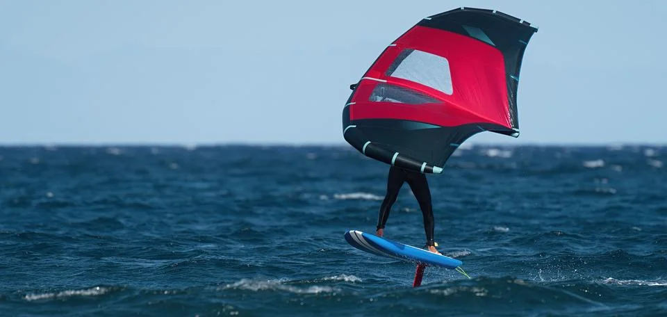 A man is wing foiling using handheld inflatable wings and hydrofoil 스톡 사진