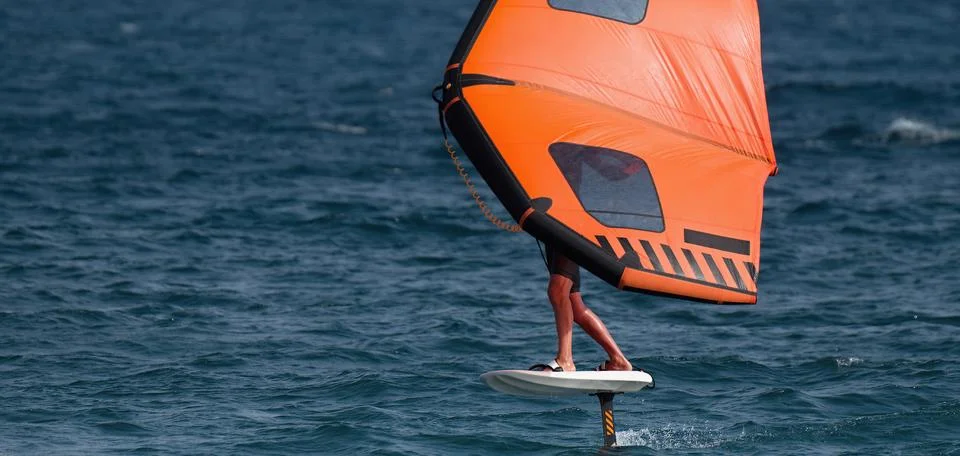 A man is wing foiling using handheld inflatable wings Stock Photos