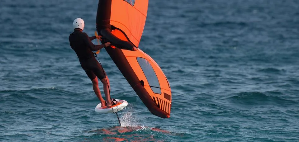 A man is wing foiling using handheld inflatable wings 스톡 사진