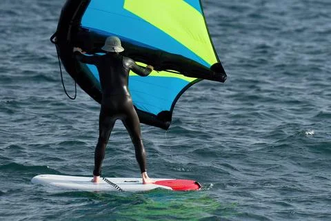 A man is wing foiling using handheld inflatable wings 스톡 사진