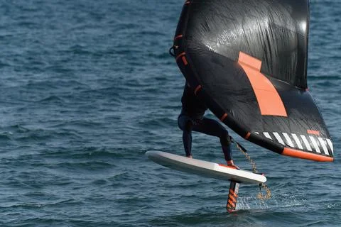 A man is wing foiling using handheld inflatable wings Stock Photos