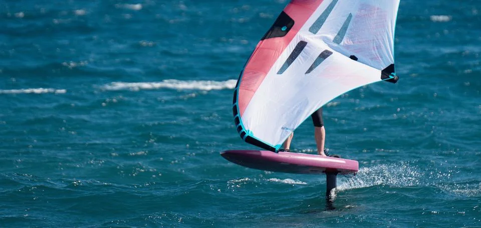 A man is wing foiling using handheld inflatable wings and hydrofoil surfboards 스톡 사진