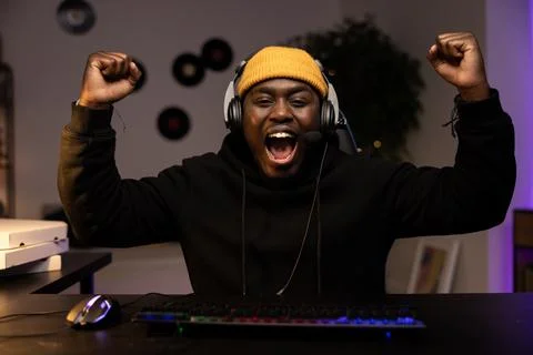 A man wins in a computer game. The boy in the headset raises his hands in the Stock-Fotos