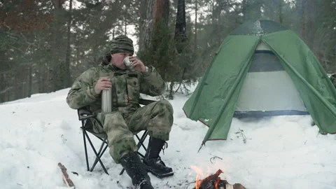 A man in a winter camp pours tea from a thermos Stockbeeldmateriaal 170156442