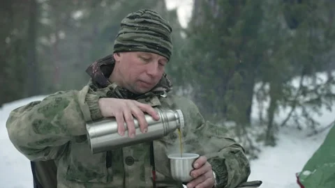 A man in a winter camp pours tea from a thermos Stock Footage 170157222