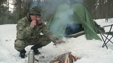 A man in a winter camp pours tea from a thermos Stockbeeldmateriaal 170440349