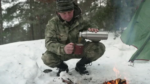 A man in a winter camp pours tea from a thermos Video stock 170441184
