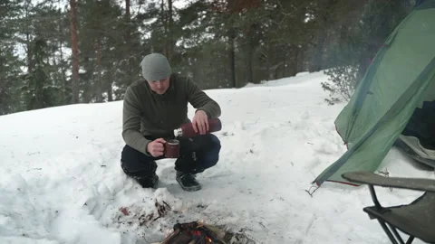 A man in a winter camp pours tea from a thermos Stockbeeldmateriaal 170441651