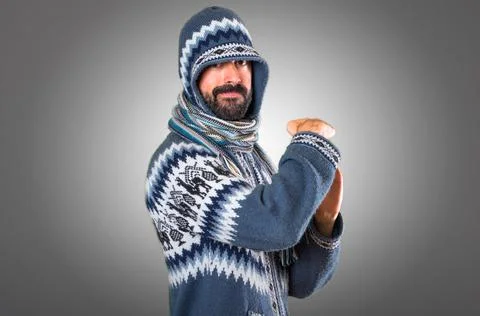 Man with winter clothes making time out gesture on grey background Stock Photos