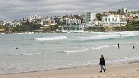 Man in winter clothes passes surfers at Bondi 4K Stock Footage 155607438