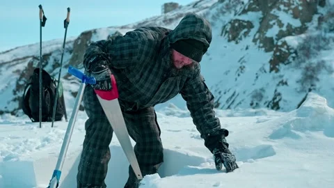Man in winter clothes saws ice blocks and constructs igloo Stock Footage 131797760