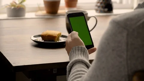 Man In Winter Clothes Scrolling Through Cell Phone While Having Breakfast Stock Footage 117692584