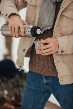 A man in the winter forest by the fire pours coffee Foto stock