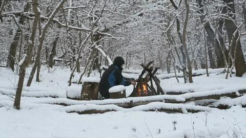 Man in the winter forest warms his hands by the fire Stock Footage 168927333
