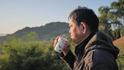 Man in a winter jacket enjoys a hot drink while admiring Stock Footage 324906437