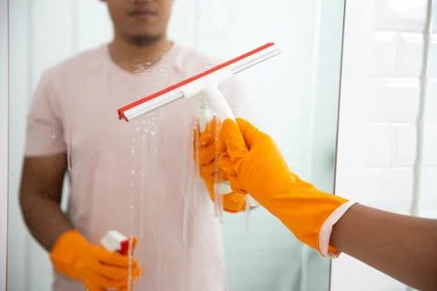 Man wipe mirror using cleaning tool Stock Photos
