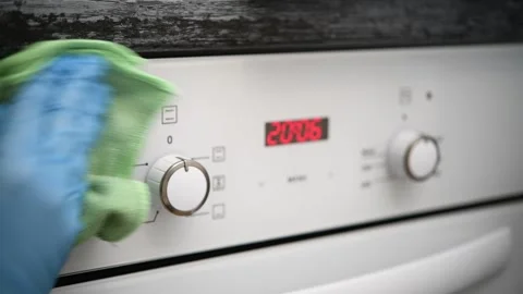 A man wipes the glass control panel of an oven in the kitchen. Stock Footage 300080718