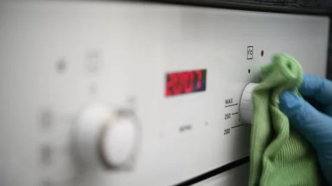 A man wipes the glass control panel of an oven in the kitchen. Video stock 300080912