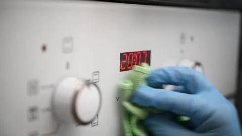 A man wipes the glass control panel of an oven in the kitchen. Stock Footage 300080964