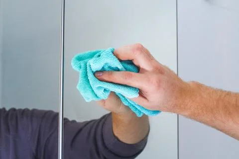 A man wipes a mirror cabinet in the bathroom with rag. Cleaning of the house Stock Photos