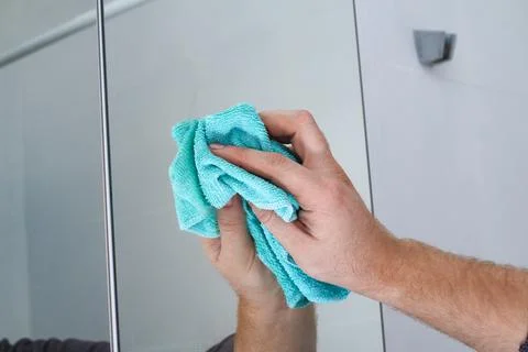 A man wipes a mirror cabinet in the bathroom with rag. Cleaning of the house Stock Photos