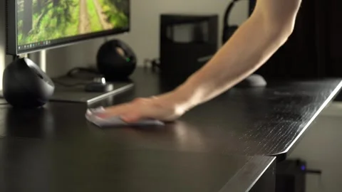 A man wipes an office table with a cloth and cleans under his computer setup - Stock Footage 246316582