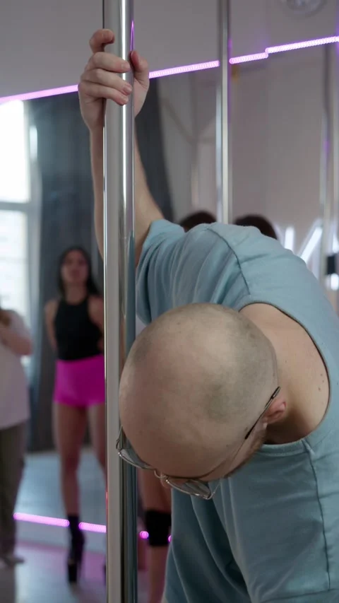 A man wipes the striptease pole and sternly stares at the camera. Stock Footage 305504713