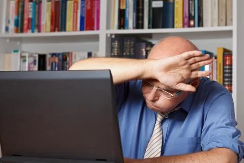 Man wiping brow computer Stock-Fotos