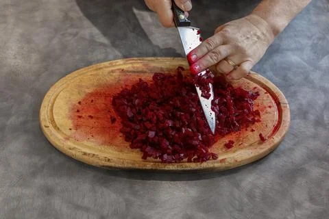 Man Wiping Chopped Beetroot off Kitchen Knife with Finger over Wooden Board Stock Photos